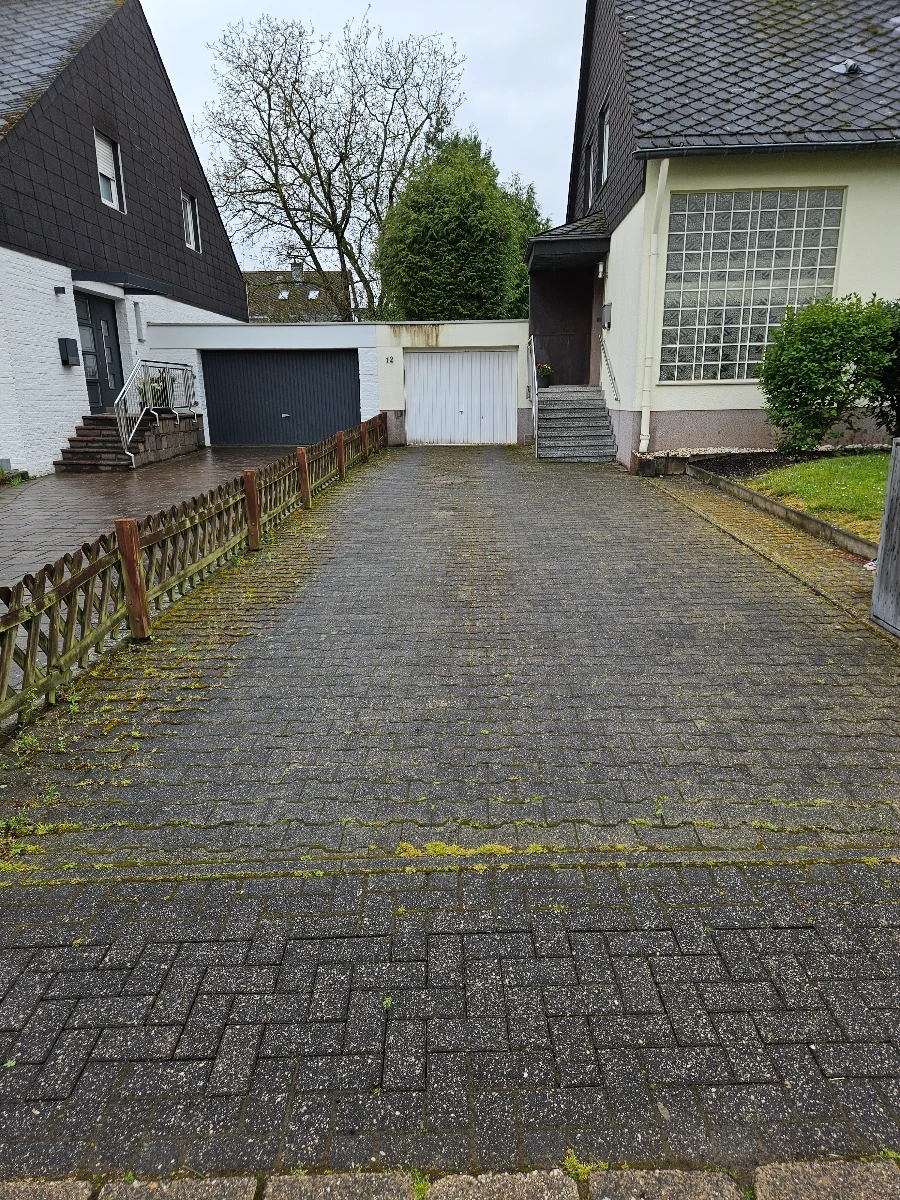 Einfahrt mit moosbewachsenen Pflastersteinen vor Garagentoren – Reinigung pflastersteine