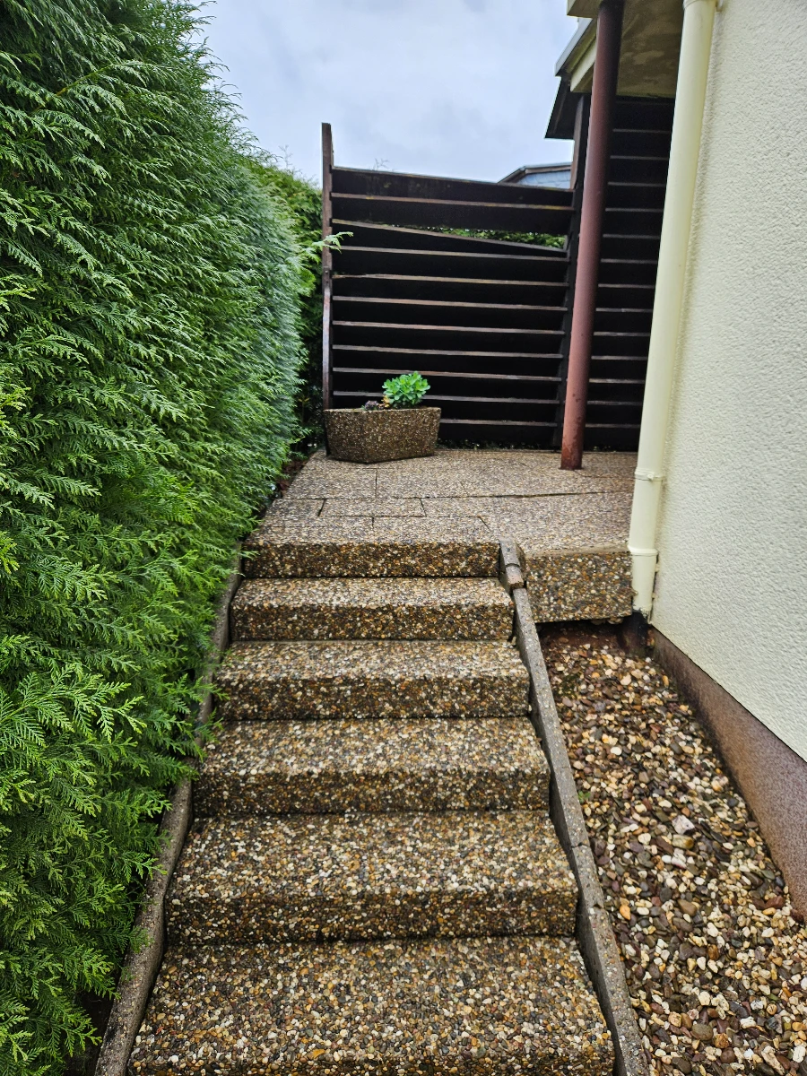 Kieselstein-Treppe und gepflasterte Fläche neben Hauswand Reinigung pflastersteine