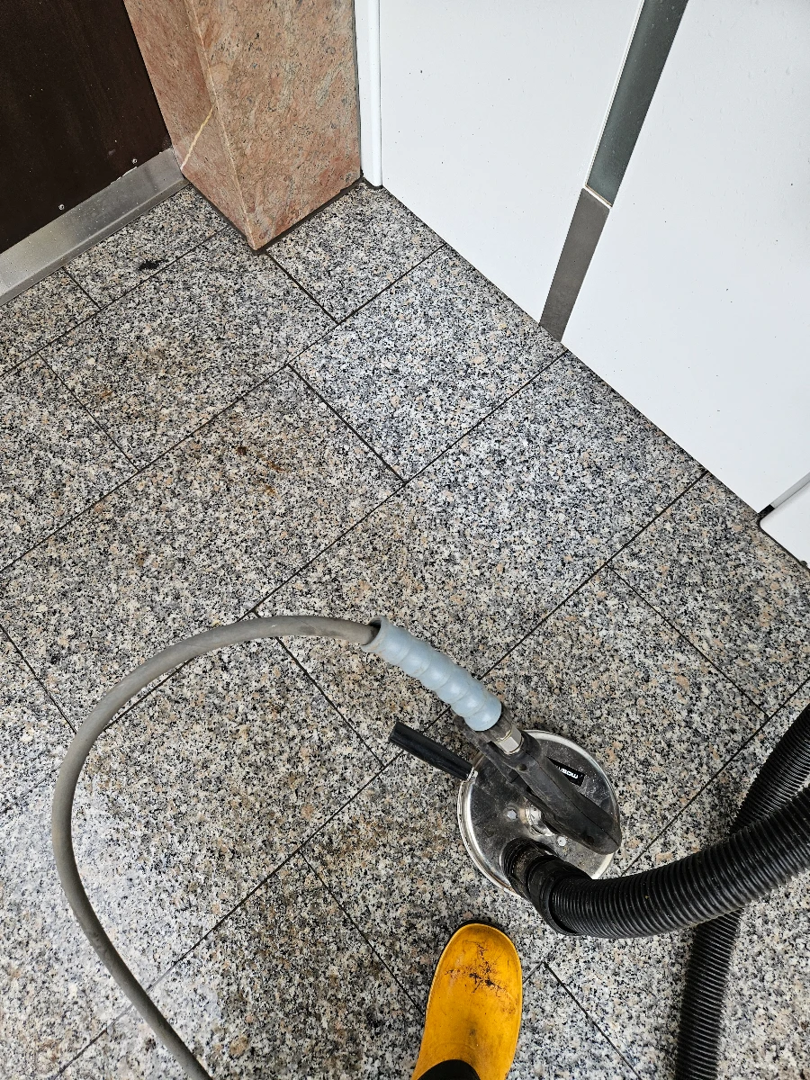 Reinigung pflastersteine auf grauen Granitplatten mit rotierender Bodendüse und Schlauch