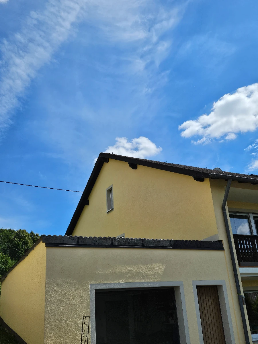 Gelbe Hausfassade mit Garage und Dachuntersicht – Fassadenreinigung