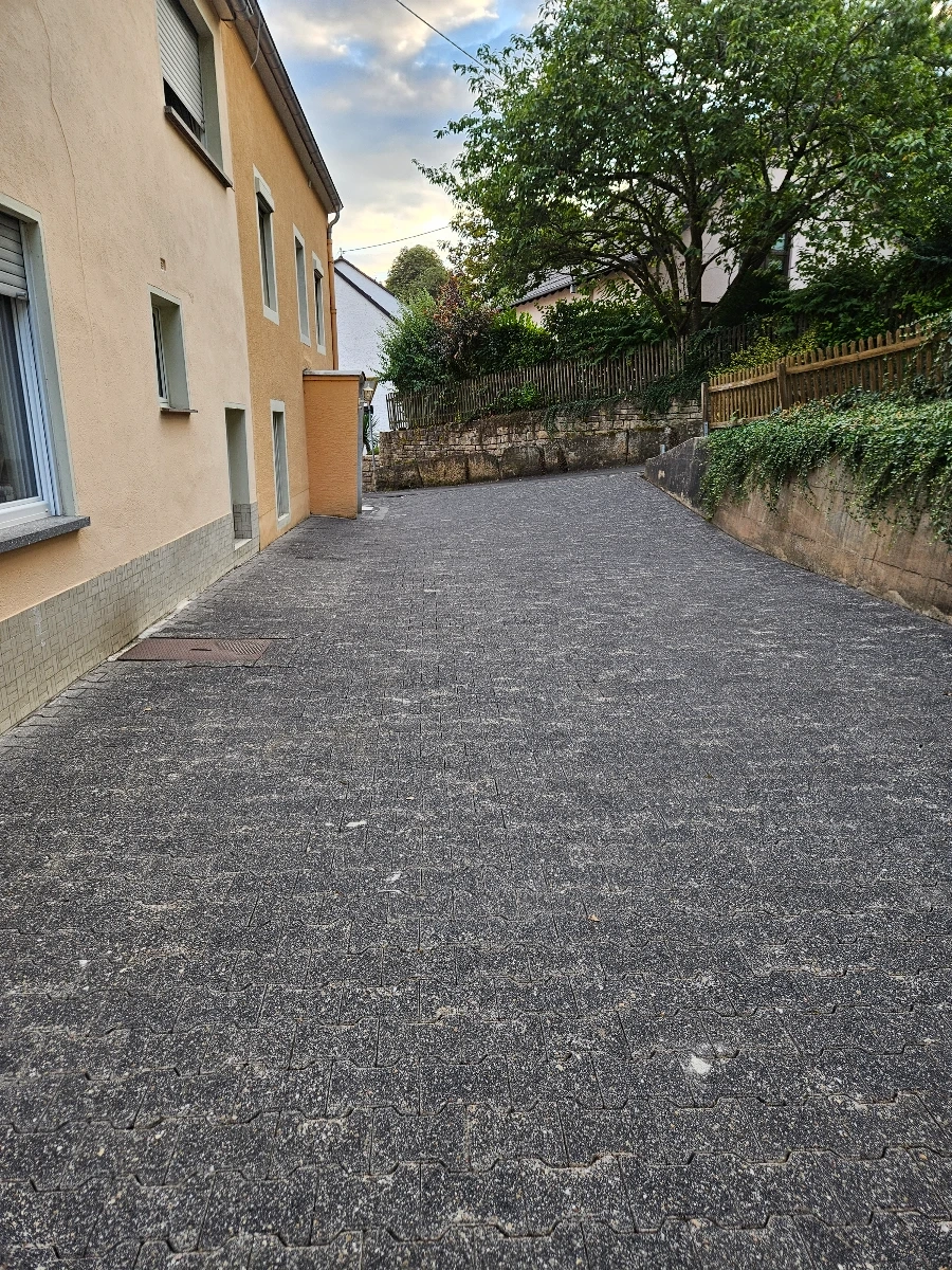 Gepflasterte Hoffläche neben Hausfassade, gereinigt im Rahmen der Reinigung pflastersteine