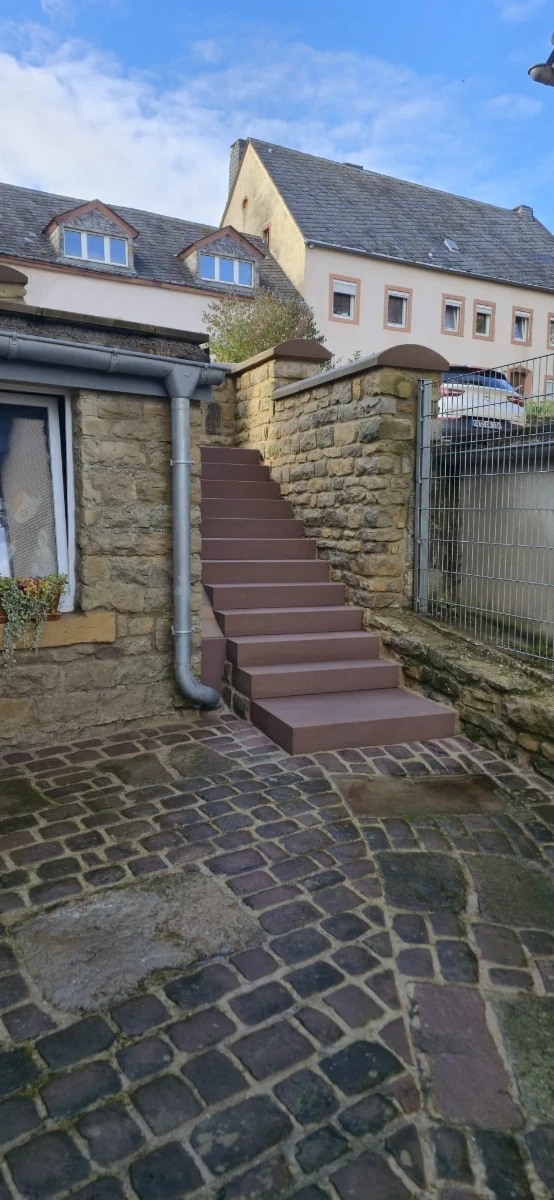 Außentreppenhaus mit frisch gereinigten Stufen aus Holz vor Sandsteinmauer nach Treppenreinigung