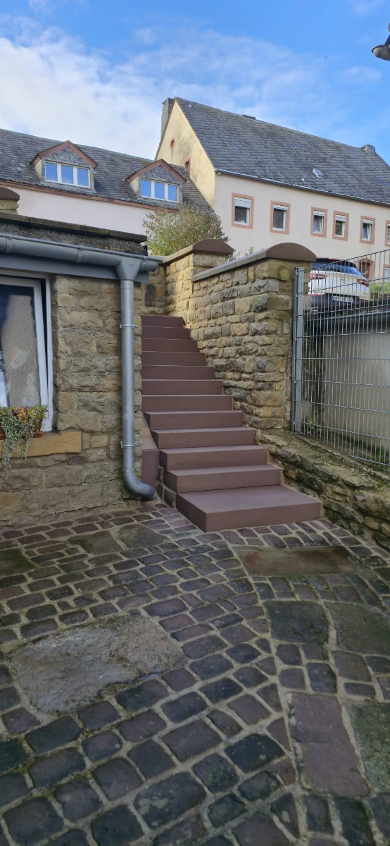 Gepflasterter Innenhof mit gereinigter Natursteintreppe an Sandsteinmauer, Hofreinigung