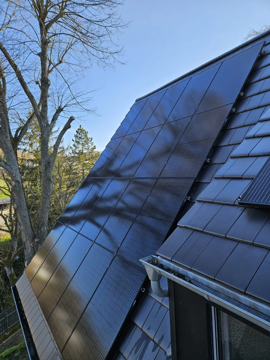 Mehrere dunkle Solarmodule auf schrägem Dach – Pv anlage reinigen